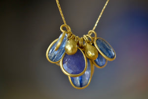 
            
                Load image into Gallery viewer, The Colette Cluster with Gold Drops, Kyanite and Tanzanite Necklace by Pippa Small is a large cluster of various sized bezel set and lightly faceted translucent stones in purple Tanzanite and blue Kyanite, accompanied by two gold beads, all in 18k yellow gold on a 20&amp;quot; golden waxed cotton cord form this necklace.
            
        
