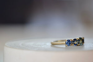 Blue Sapphire Five Stone Ring by Elizabeth Street Jewelry and Katie Finn is a one of a kind Sapphire ring with five stones in gradient blue ombré to green, each in an eagle claw prong setting on a satin brushed 14k yellow gold band available at OK. 