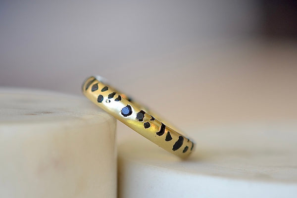 The Black Sapphire Confetti Band in size 8 designed by Polly Wales is a narrow 18k gold wedding band/ring speckled with black sapphires around the circumference. Cast not set. Made in Los Angeles. 