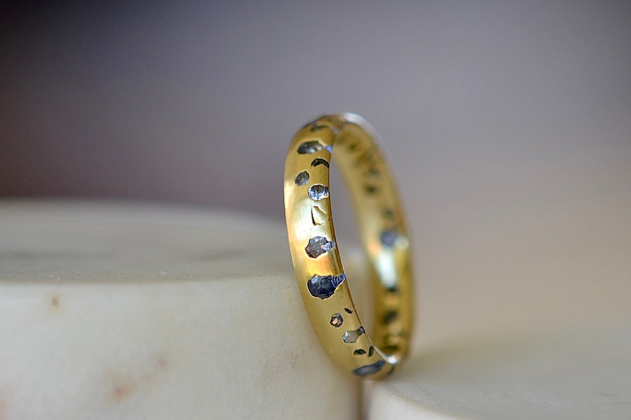 The Cornflower Blue Sapphire Confetti Band designed by Polly Wales is a narrow 18k yellow recycled gold wedding band/ring with speckled ombre light blue sapphires around the circumference. It is cast not set and handmade in Los Angeles.