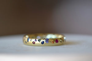 Alternate view of Polly Wales Classic Rainbow Confetti Band Ring in 18k recycled yellow gold with green, yellow, orange, blue, purple and pink sapphires and cast not set. Size 7.