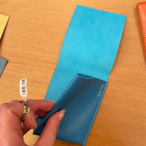 Simple Flap wallet in turquoise leather and white stitching from architect Alice Park shown empty..