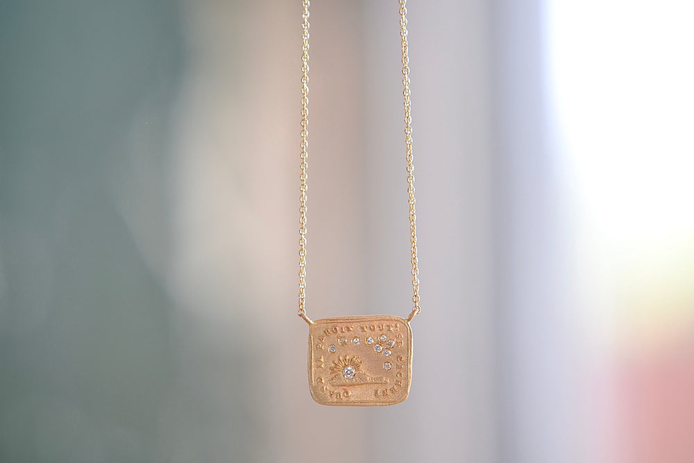 Makiko Wakita Motto Conceals All Necklace A pendant with satin finish on a 14k gold chain image of the sun and stars with 10 ten diamonds : Quand II Paroit Tout Se Cachent, meaning, 'When it Appears, It Conceals All