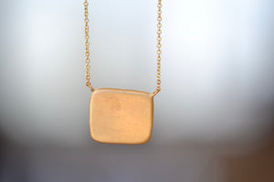 Makiko Wakita Motto Conceals All Necklace A pendant with satin finish on a 14k gold chain image of the sun and stars with 10 ten diamonds : Quand II Paroit Tout Se Cachent, meaning, 'When it Appears, It Conceals All