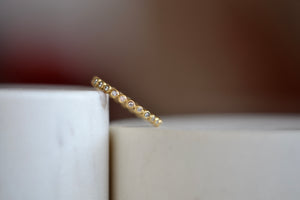 1mm thick porch band by Marian Maurer is a wedding band in bezel set round diamonds that is 1mm tall. Tilted view.