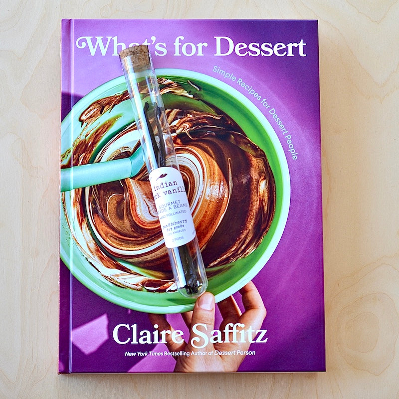 Indian Black Vanilla Pods in vial on baking book.