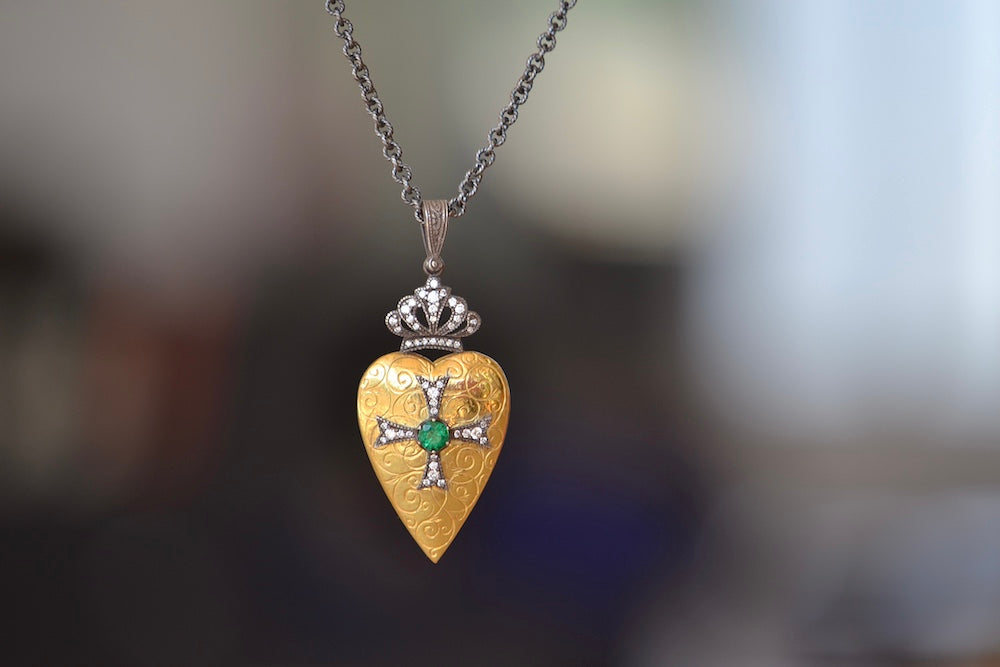 Heart Pendant with Crown Love Locket by Arman Sarkysian is a shaped heart in 22k gold with beautiful detailing, an oxidized silver cross in the middle and a crown on top, both, adorned with diamonds and one green emerald, hangs on a beautiful chain in oxidized silver.