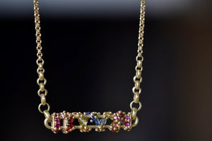 
            
                Load image into Gallery viewer, Close up of Horizontal Fontaine Bar Necklace in Rainbow by Polly Wales is An oval and three dimensional bar in 18K yellow gold holds a vine of encrusted and inverted rainbow sapphires in pink, fuchsia, blue, yellow, green and red that have been cast and are accompanied by matte gold dots. Recycled Gold. Cast Not Set. Handmade in Los Angeles.
            
        